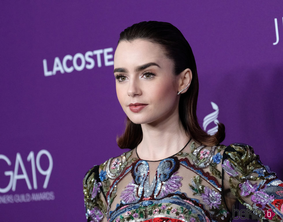 Lily Collins peina su cabello hacia atrás acabándolo en un rulo