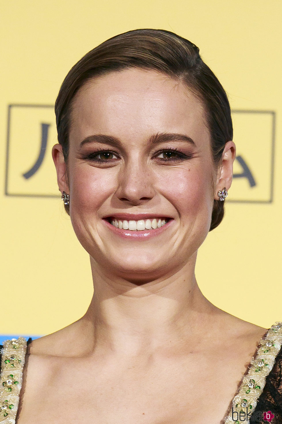 Brie Larson con moño bajo muy pulido y raya al lado